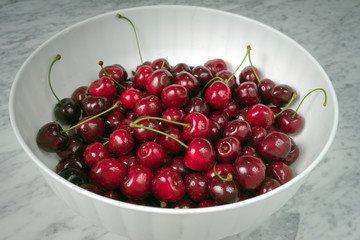 Ripe cherries in a white plastic bowl