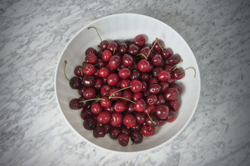 Ripe cherries in a white plastic bowl