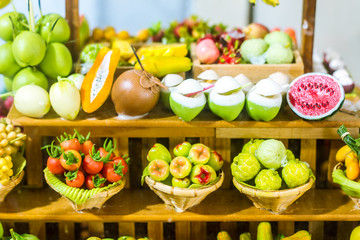 close up Miniature clay figurine Thailand's floating market,Miniature boat carrying tropical fruit on wood background