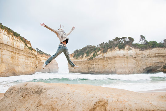 Young man jumping by Loch Ard Gorge, Melbourne, Australia