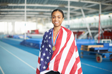 Young female athlete wrapped in US flag with gold medal