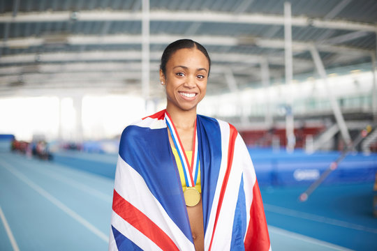 Young female athlete wrapped in UK flag with gold medal