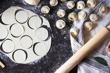 Preparation of pelmeni. Top view. Ingredients on black table. Traditional Russian cuisine.