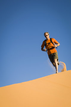 Male hiker running across Star Dune, Coral Pink Sand Dunes State Park, Utah, USA