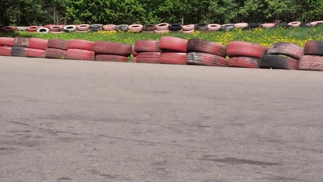 People on karting cars pass by camera driving on karting track.