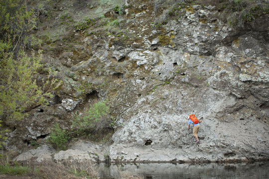 Young man climbing on lakeside rock, Malibu Creek State Park, California, USA