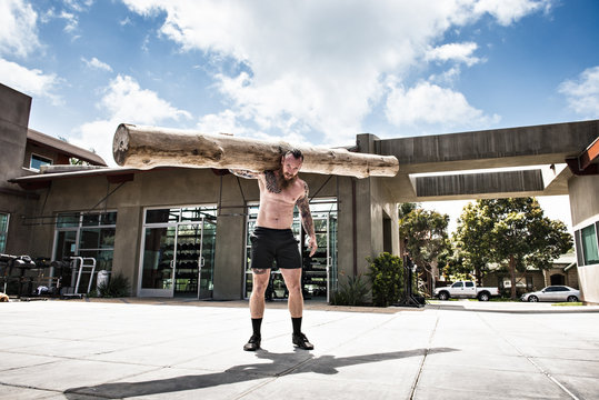 Man carrying log on shoulders outdoors