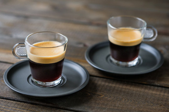 Two cups of espresso on a wooden table