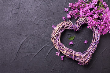 Decorative heart and colorful spring lilac flowers  on black textured background.
