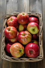 basket with red ripe apples on a brown wooden table