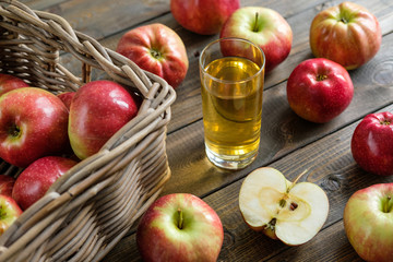 A glass of juice on a background of red ripe apples