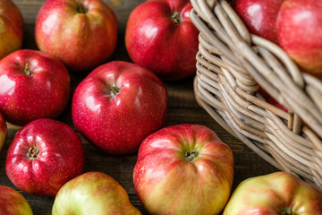 basket with red ripe apples on a brown wooden table