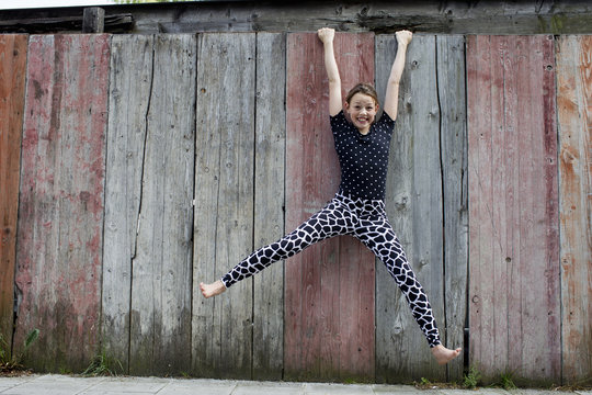 Teenage girl hanging from wooden fence