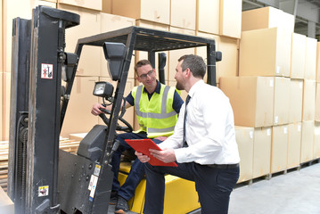 Teamwork - Manager und Arbeiter im Gespräch in einem Warenlager in der Logistikbranche