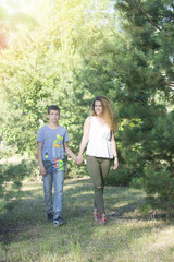 Brother and sister having fun at the park. Big sister and little brother walking through a park and bonding. Smiling and looking at the camera.