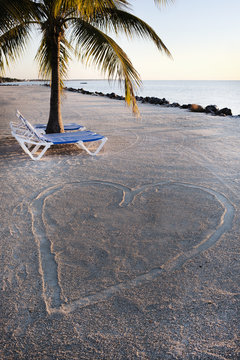 Sun loungers beside heart shape on sandy beach, Islamorada, Florida Keys, USA