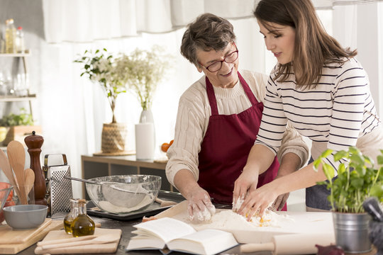 Grandmother teaching granddaughter baking cake