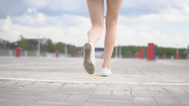 Woman legs jogging on the street, super slow motion