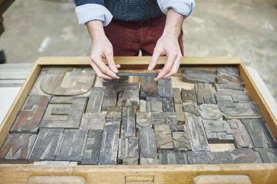 Young mans hands holding letterpress letter in traditional print workshop