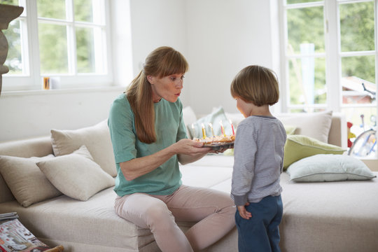 Boy and mid adult woman blowing out birthday candles