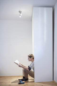 Mature woman sitting reading instruction manual for flatpack closet