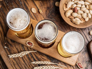 Glasses of beer and snacks on the wooden table.