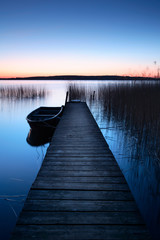 Obraz premium Calm Lake at Sunrise, Wooden Pier with Fishing Boat