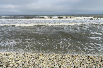 Landscape with sea view, waves and sea shells, clouds, photographed in Gura Portitei, Romania, in cloudy spring day