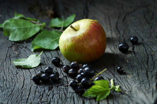 Cox's apples and blackcurrants on old wooden surface