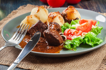 Pork meat stew served with potatoes and vegetable salad
