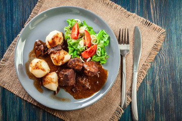 Pork meat stew served with potatoes and vegetable salad