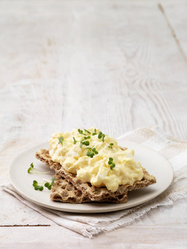 High angle view of egg mayonnaise garnished with cress on crackers on whitewashed wood surface
