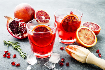 Red cocktail with blood orange and pomegranate. Refreshing summer drink on gray stone or concrete...