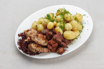 Grilled meat and young potatoes with dill sauce on a white plate