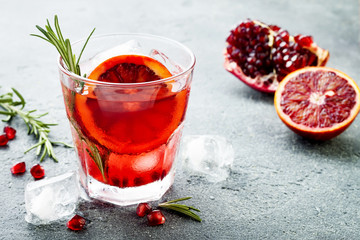 Red cocktail with blood orange and pomegranate. Refreshing summer drink on gray stone or concrete...
