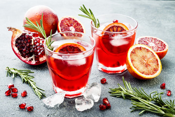 Red cocktail with blood orange and pomegranate. Refreshing summer drink on gray stone or concrete...