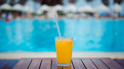 orange cocktail on wooden table background pool