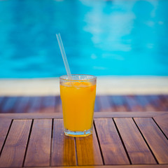 orange cocktail on wooden table background pool