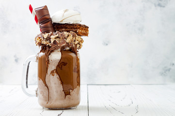Chocolate indulgent exreme milkshake with brownie cake, marshmallow and sweets. Crazy freakshake...