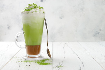 Matcha latte with salted caramel in tall glass. Copy space