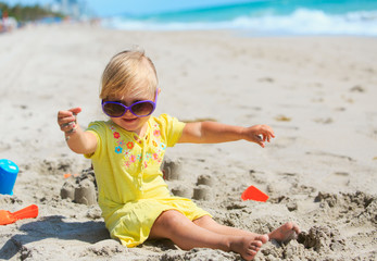 cute little girl play with sand on beach