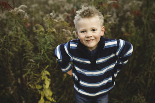 High angle portrait of boy, hands on hips looking at camera smiling