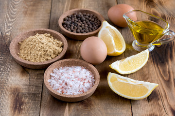 Mayonnaise ingredients on wooden background Salt Pepper Eggs Lemon Oil Rustic Ingredients for sauce