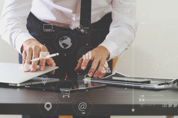 close up of businessman working with smart phone and digital tablet and laptop computer on wooden desk in modern office with virtual icon diagram