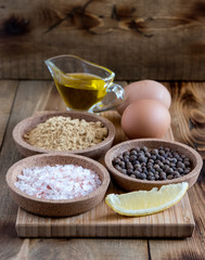Mayonnaise ingredients on wooden background Salt Pepper Eggs Lemon Oil Rustic Ingredients for sauce Vertical photo