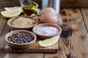 Mayonnaise ingredients on wooden background Salt Pepper Eggs Lemon Oil Rustic Ingredients for sauce Copy space