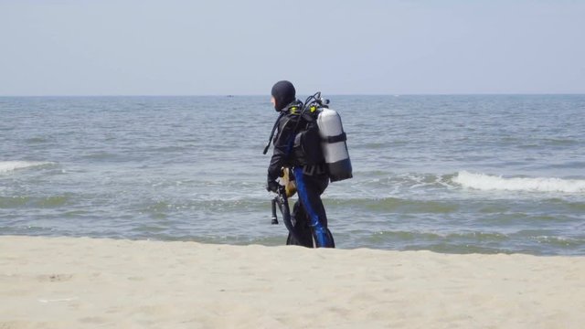 Scuba diver walking back to shore along the sea coast.