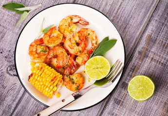 Grilled shrimps and corn garnished with lime and sage leaves. Prawns on white plate. View from above, top studio shot