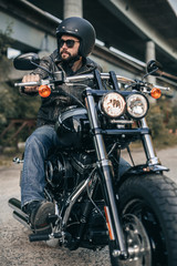 Biker in helmet and leather jacket sitting on a motorcycle. Freedom and travel concept.