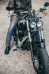 Fototapeta na wymiar Closeup motorcycle detail headlight. Man in jeans seat on the motorcycle.